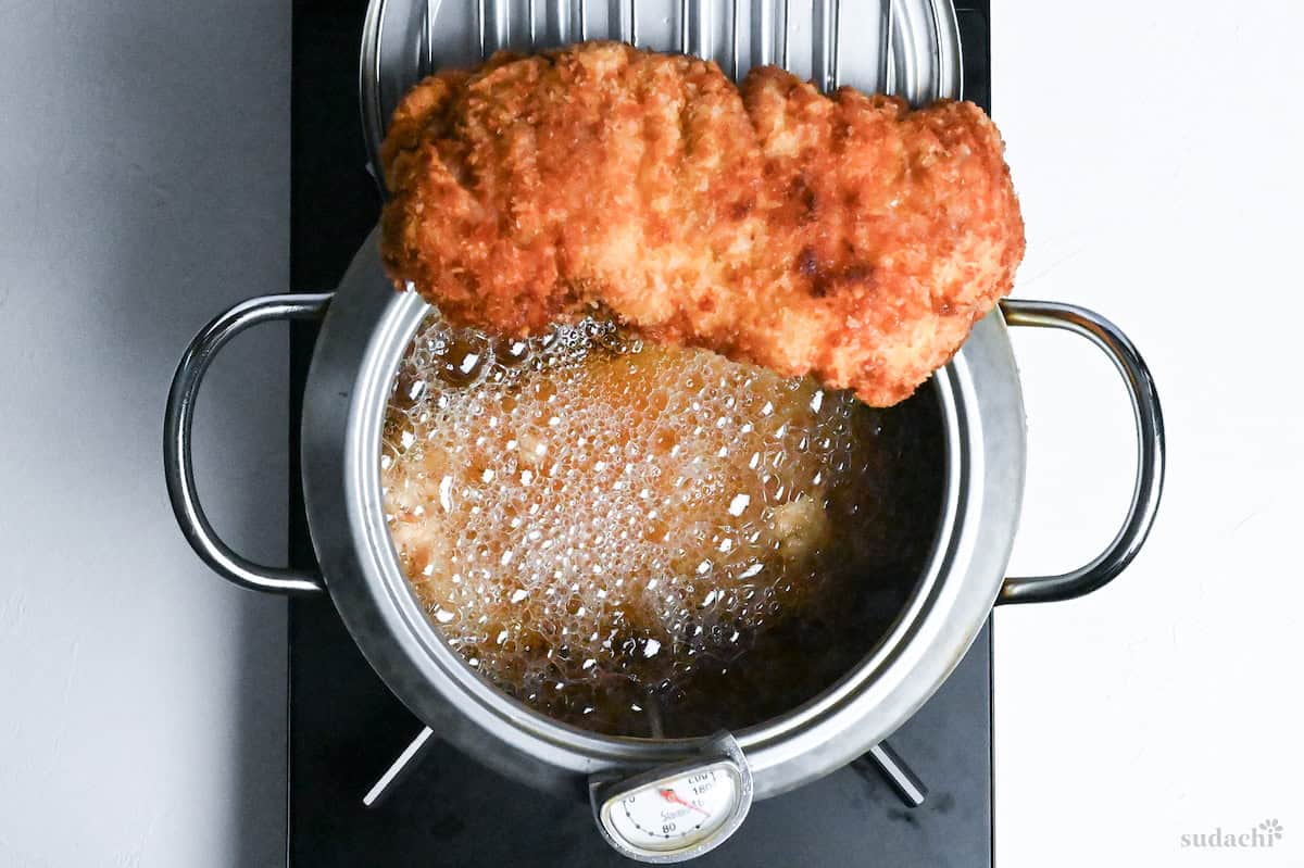 chicken katsu resting on a wire rack above a Japanese tempura frying pot
