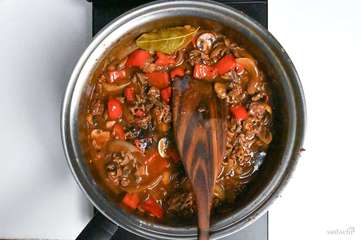 simmering beef hayashi with bayleaf in a pan