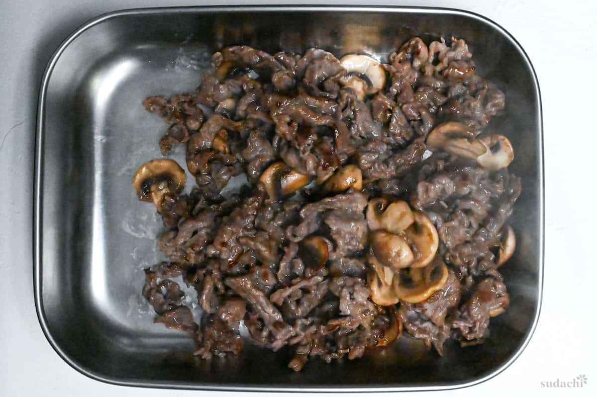 browned beef and mushrooms in a steel container