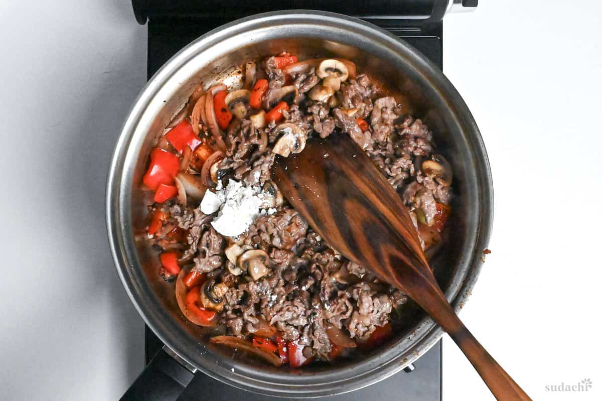 beef, mushrooms and flour added to pan with onion and bell peppers