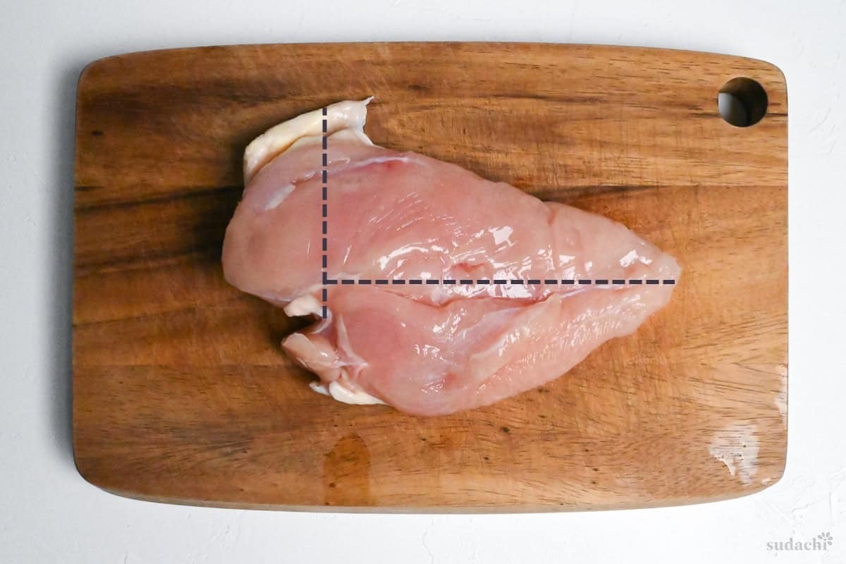 whole chicken breast on a cutting board with dotted line marking how to cut it into thirds