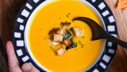 Japanese style kabocha soup topped with homemade croutons and kabocha skin in a white bowl with blue patterned rim