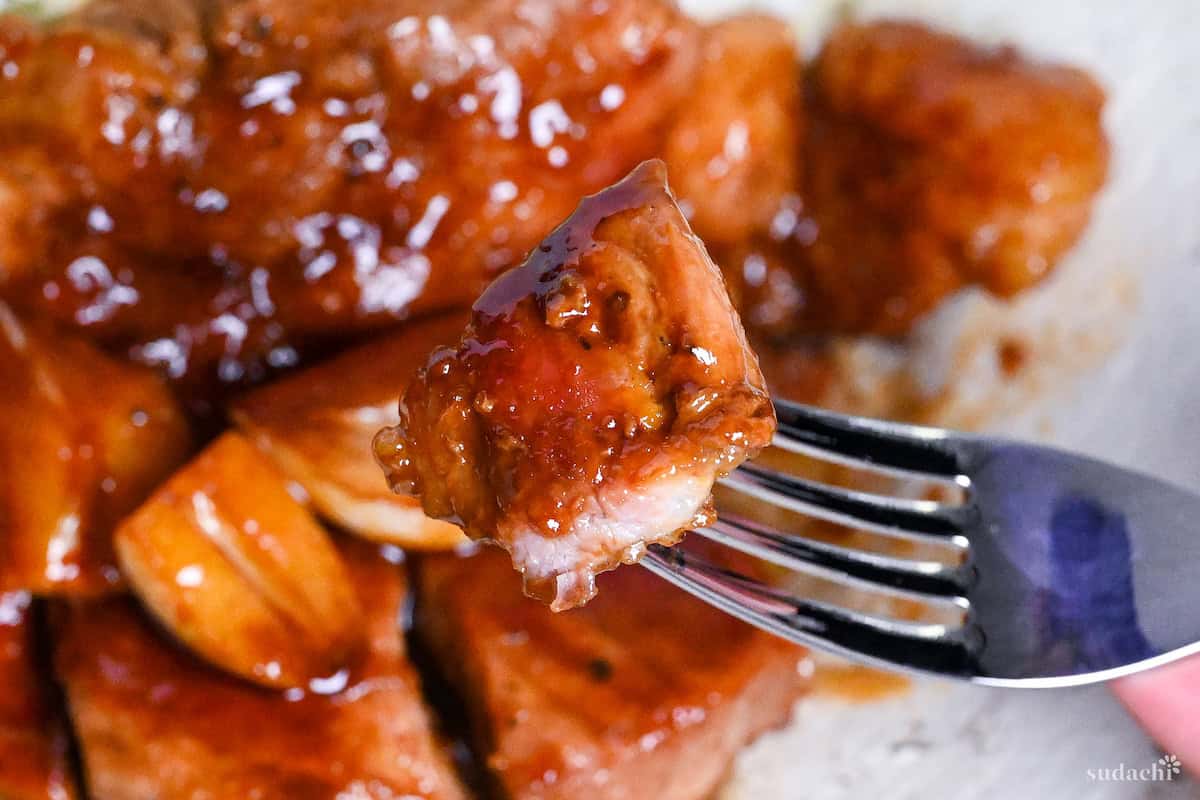 A piece of tonteki pork steak held up with a silver fork