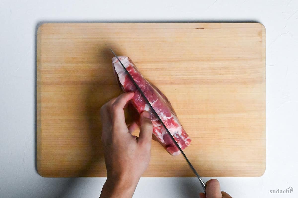 cutting a pork shoulder loin in half horizontally to make two pork steaks