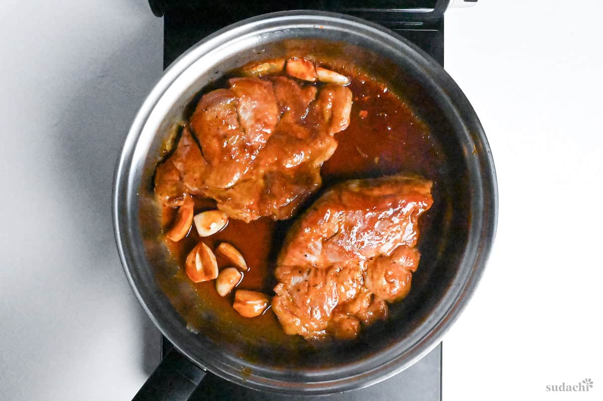 Japanese tonteki pork steaks with sauce in a stainless steel pan on the stove