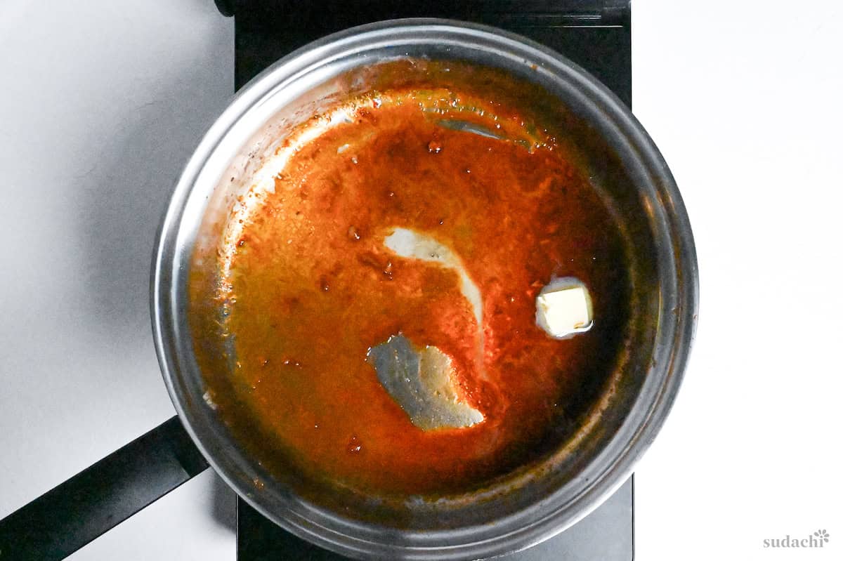 butter in tonteki sauce in a stainless steel pan on the stove