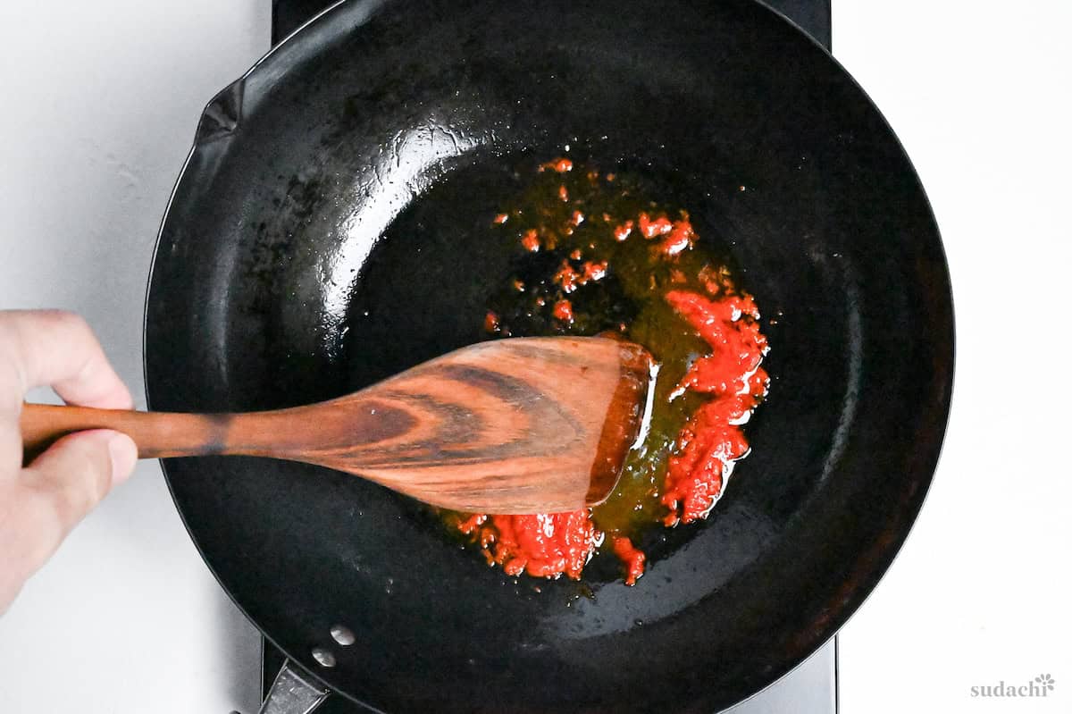 frying chili bean paste in a shrimp-infused oil in a wok