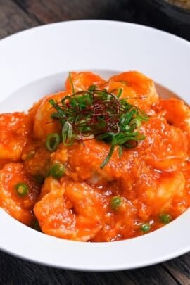 ebi chili topped with chopped green onions, green peas and chili threads in a white dish thumbnail