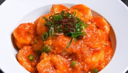 ebi chili topped with chopped green onions, green peas and chili threads in a white dish thumbnail