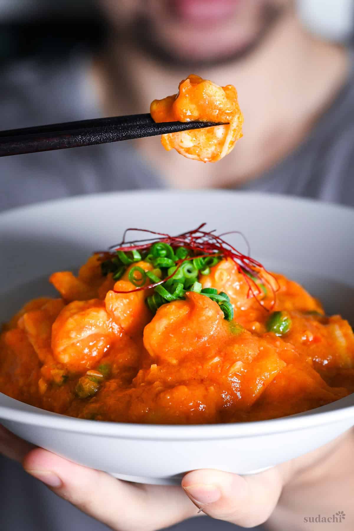Yuto Omura holding up a white bowl of ebi chili