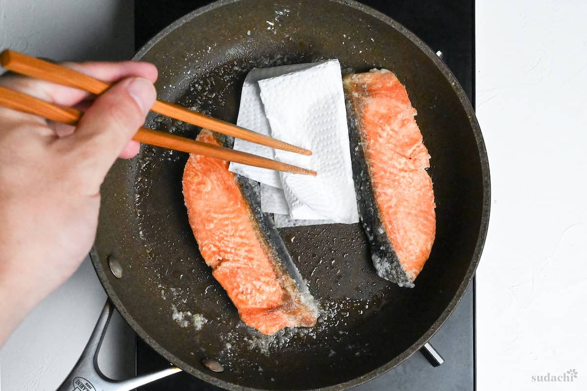 wiping excess oil out of a pan with kitchen paper