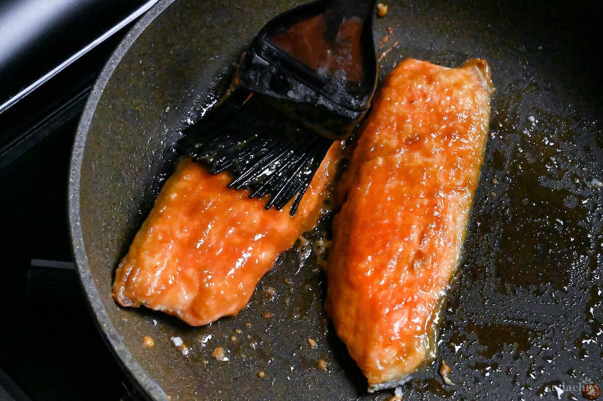 close up of brushing pan-fried salmon fillets with miso glaze