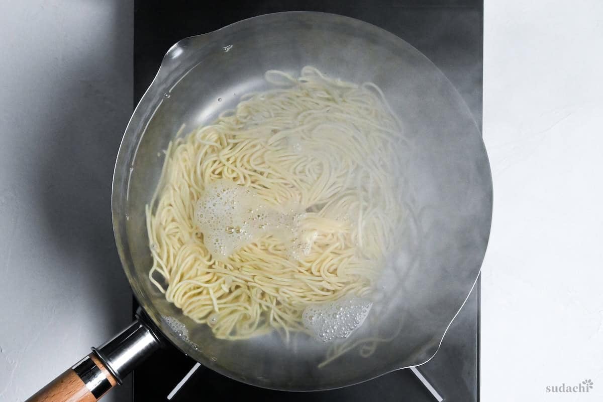 ramen noodles boiling in water in a pot on the stove