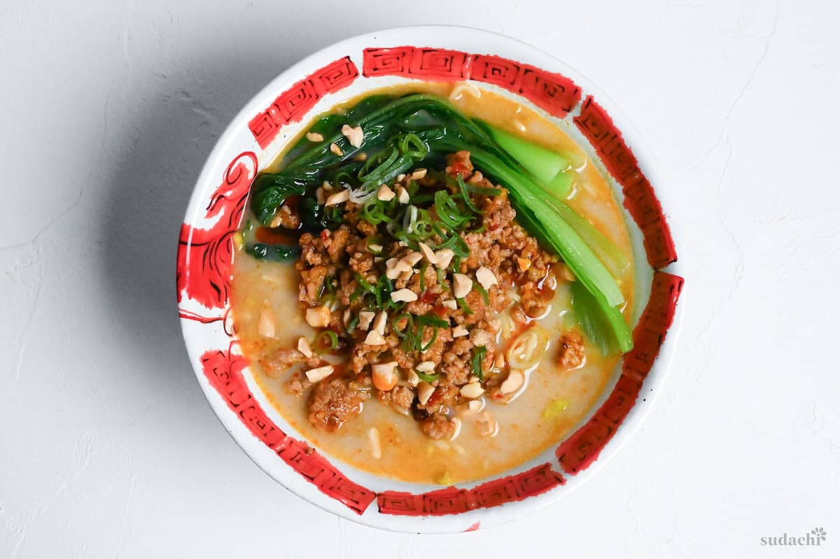 Tantanmen in a white and red ramen bowl topped with crushed peanuts