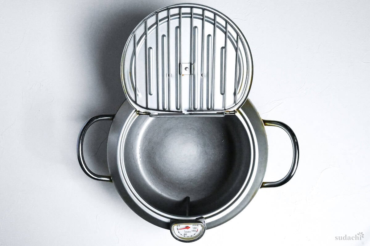 Japanese tempura frying pot with wire draining rack lid on a white background