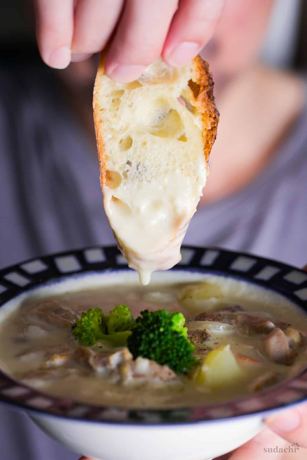 Yuto Omura holding up a slice of baguette that has been dipped in chicken cream stew