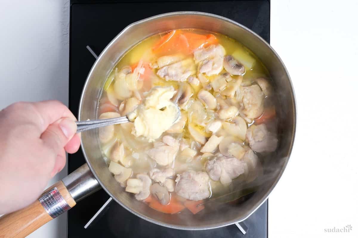adding butter, flour and miso roux to pot of chicken cream stew