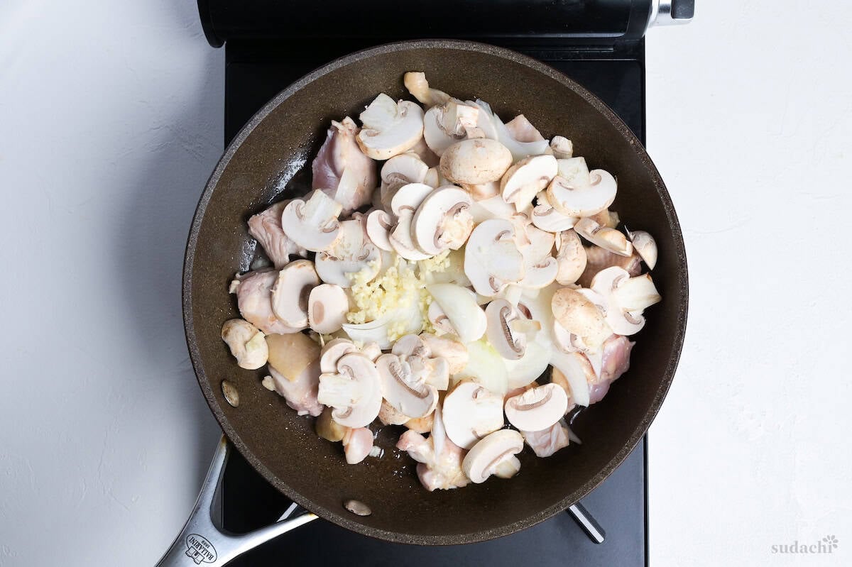 chicken, onion, mushrooms and garlic frying in a pan on the stove top