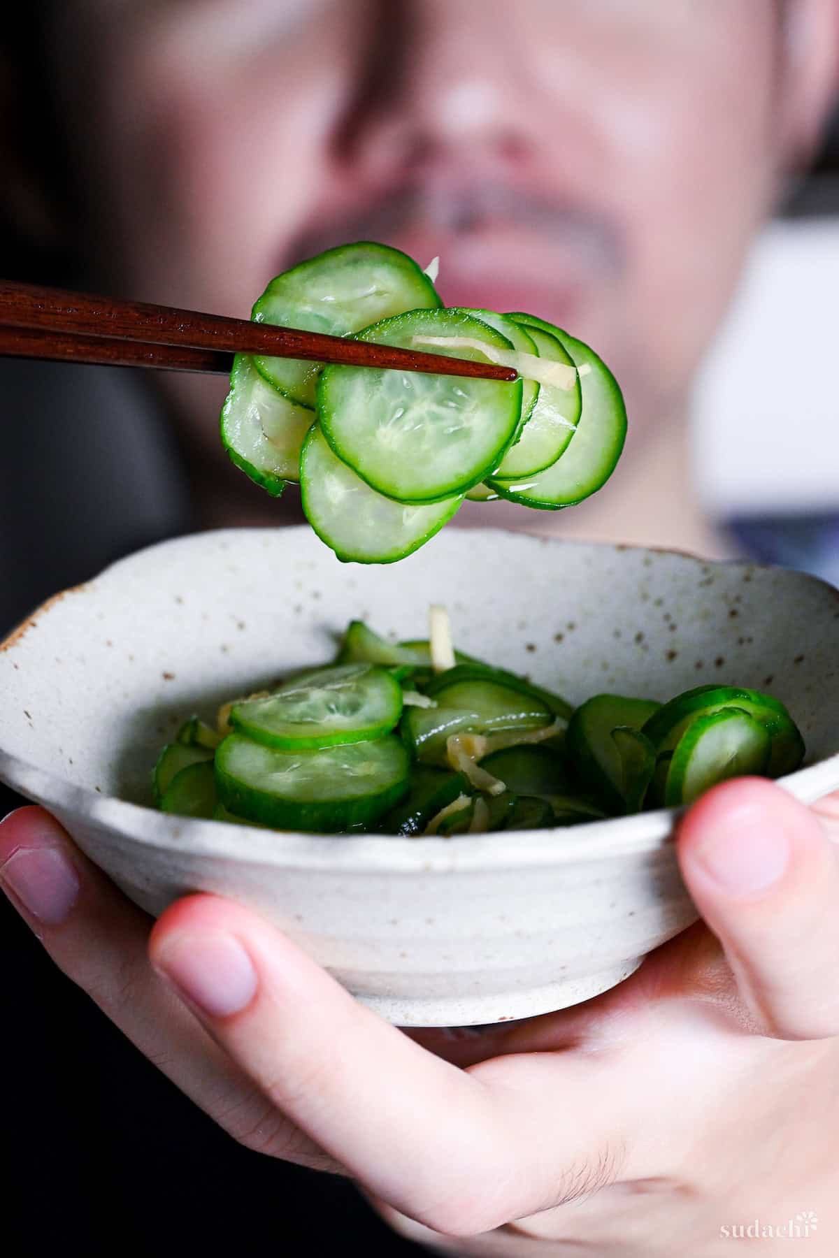 Yuto Omura holding up sunomono with wooden chopsticks