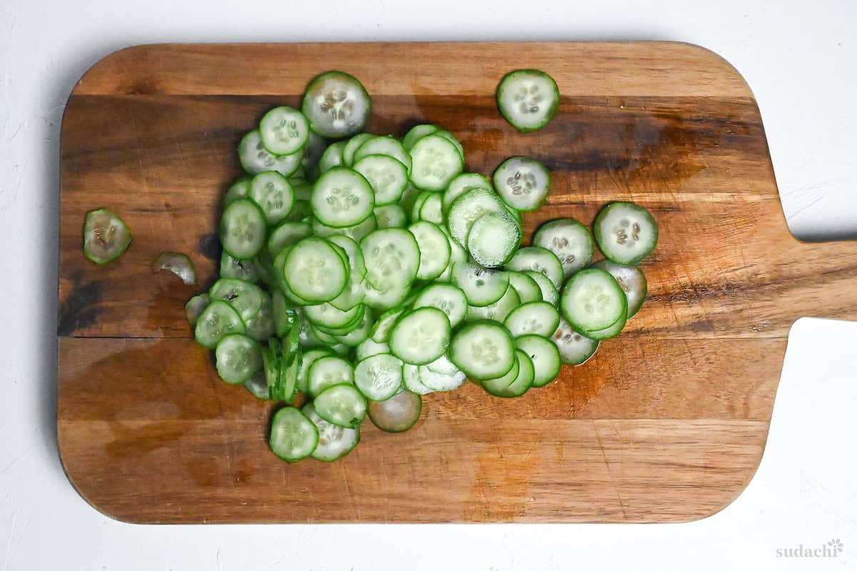 thinly sliced Japanese cucumber on a wooden cutting board