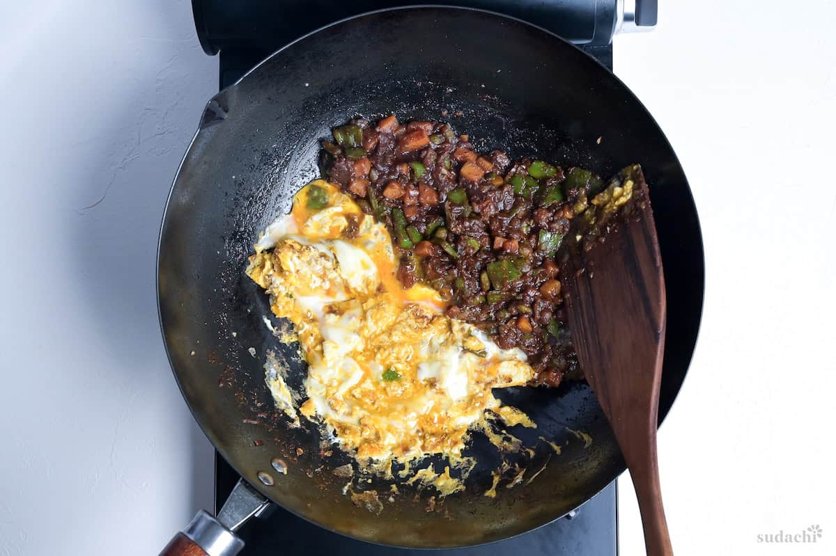 Half cooked eggs and flavored vegetables in a wok (for makign Japanese curry fried rice)