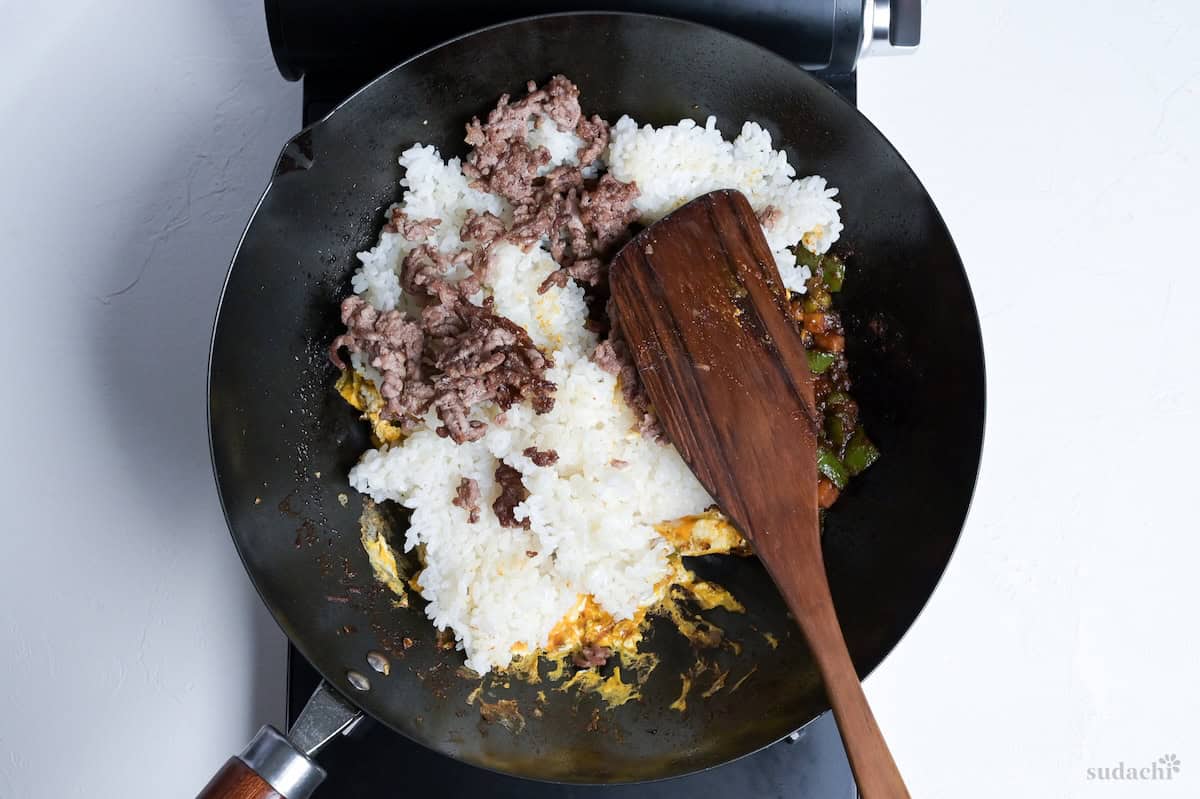 Cooked and cooled Japanese rice, and cooked ground pork added to the pan with eggs and curried vegetables