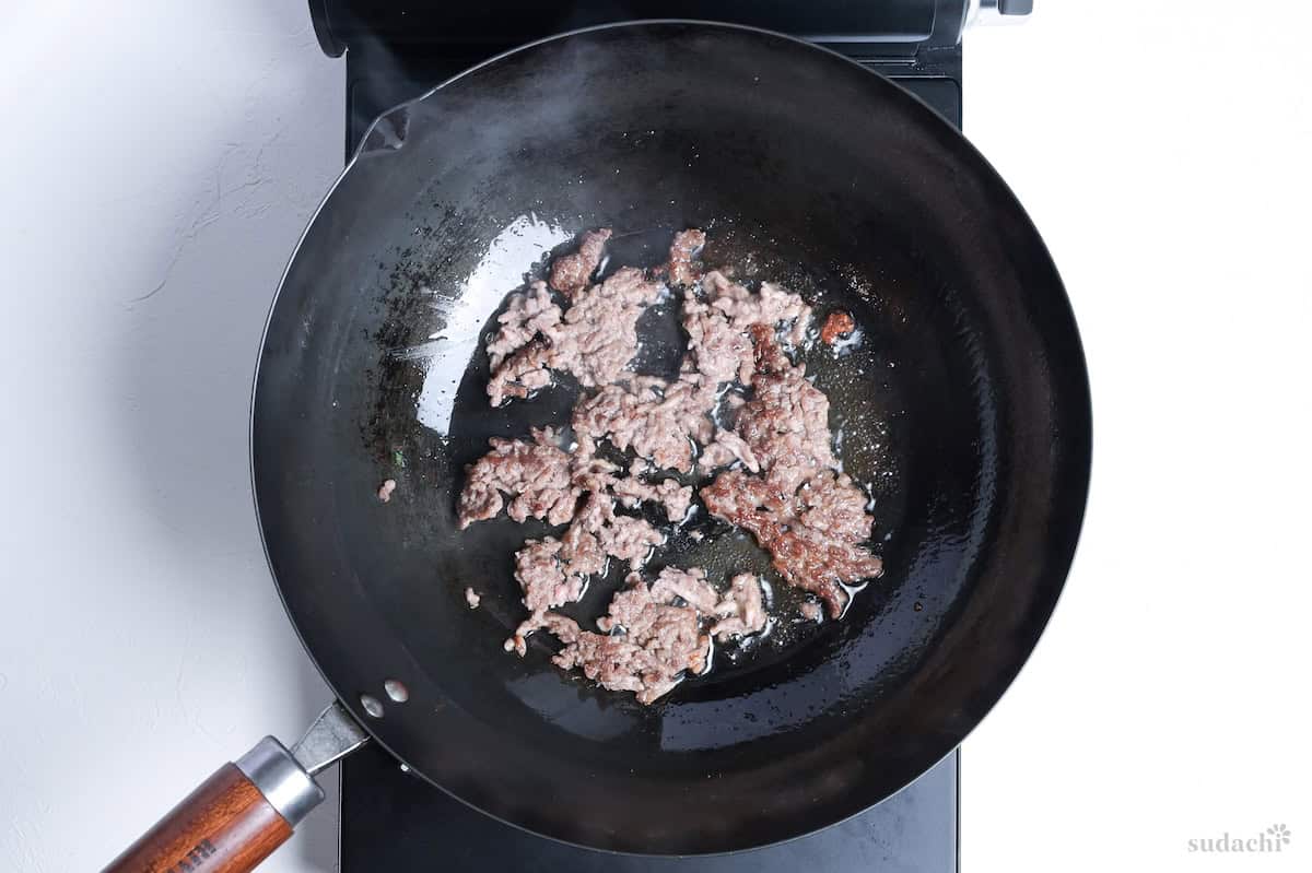 Browned ground pork in a wok on the stove
