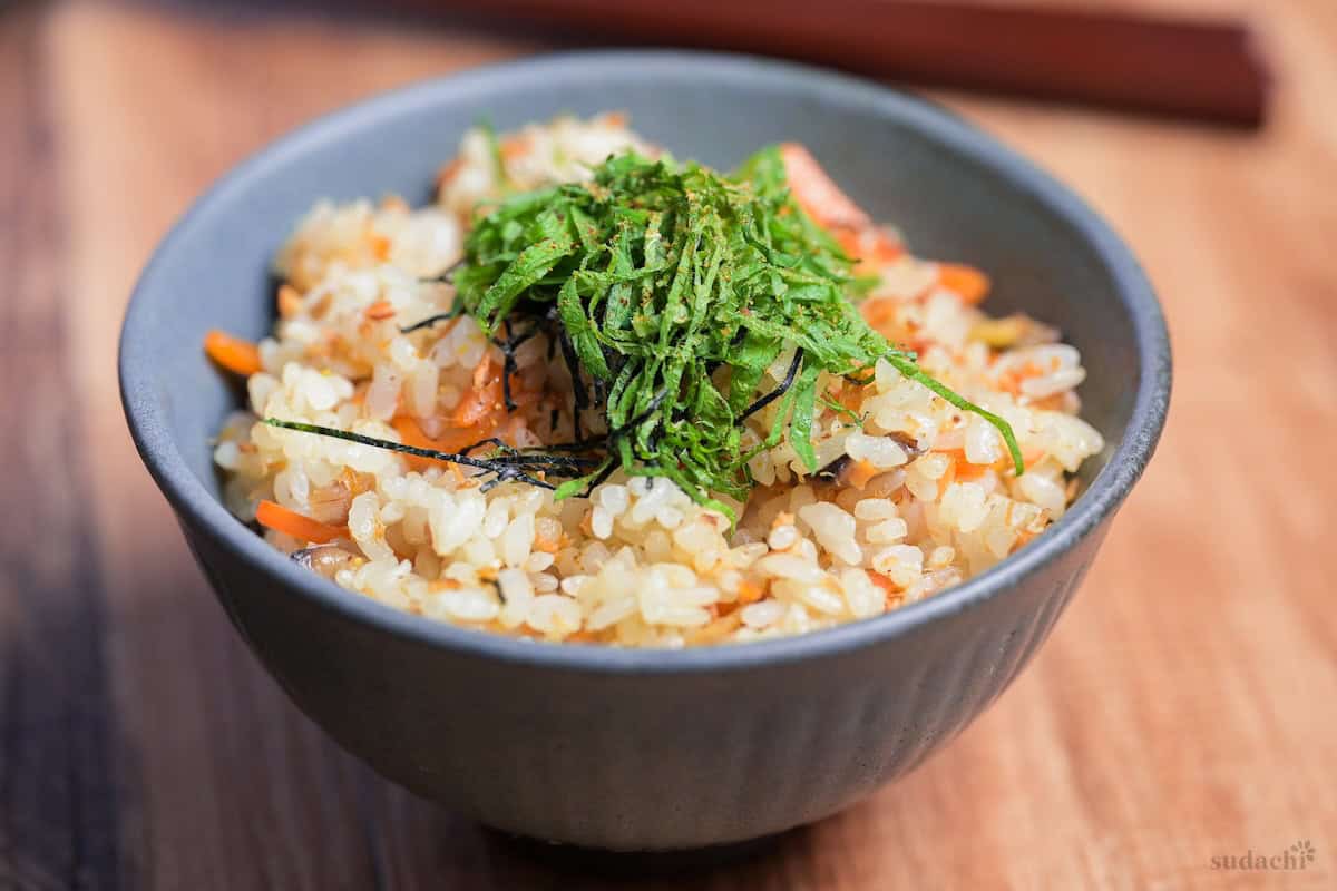 Salmon Maze Gohan topped with shredded nori and shiso leaves in a gray ceramic Japanese rice bowl