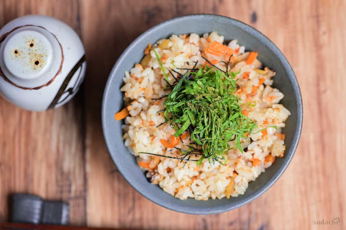 Salmon Maze Gohan topped with shredded nori and shiso leaves in a gray ceramic Japanese rice bowl