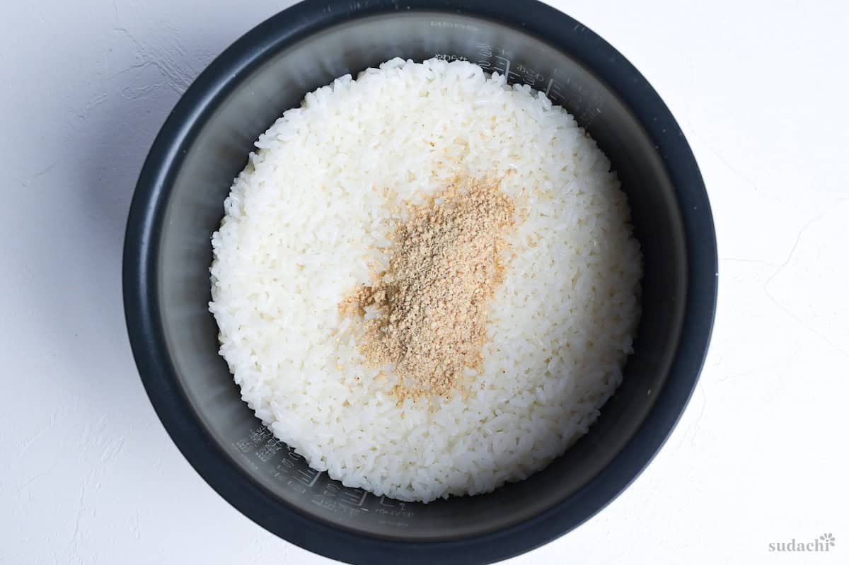 freshly cooked rice in a rice cooker pot topped with ground sesame seeds