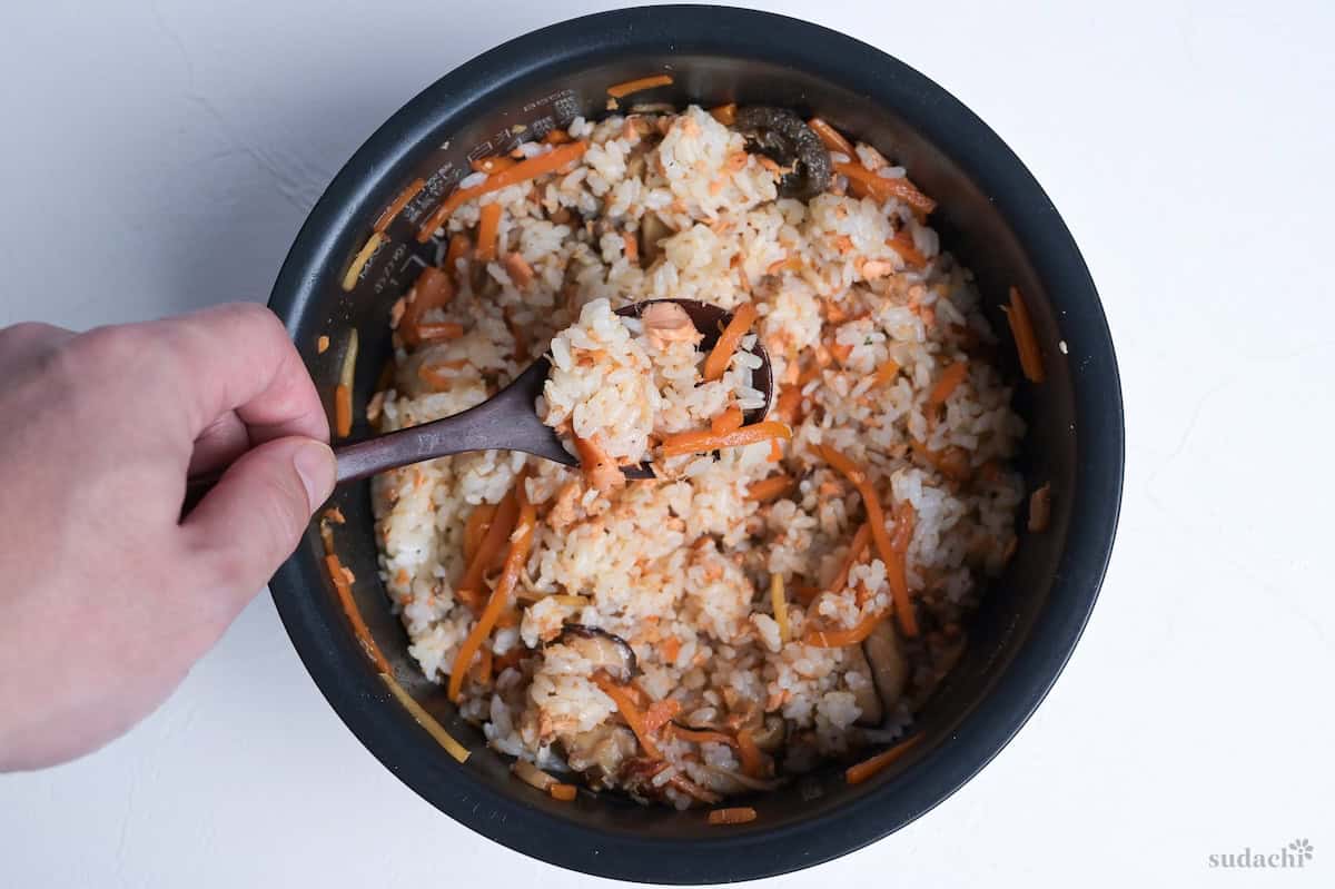a spoonful of salmon maze gohan held over rice cooker pot