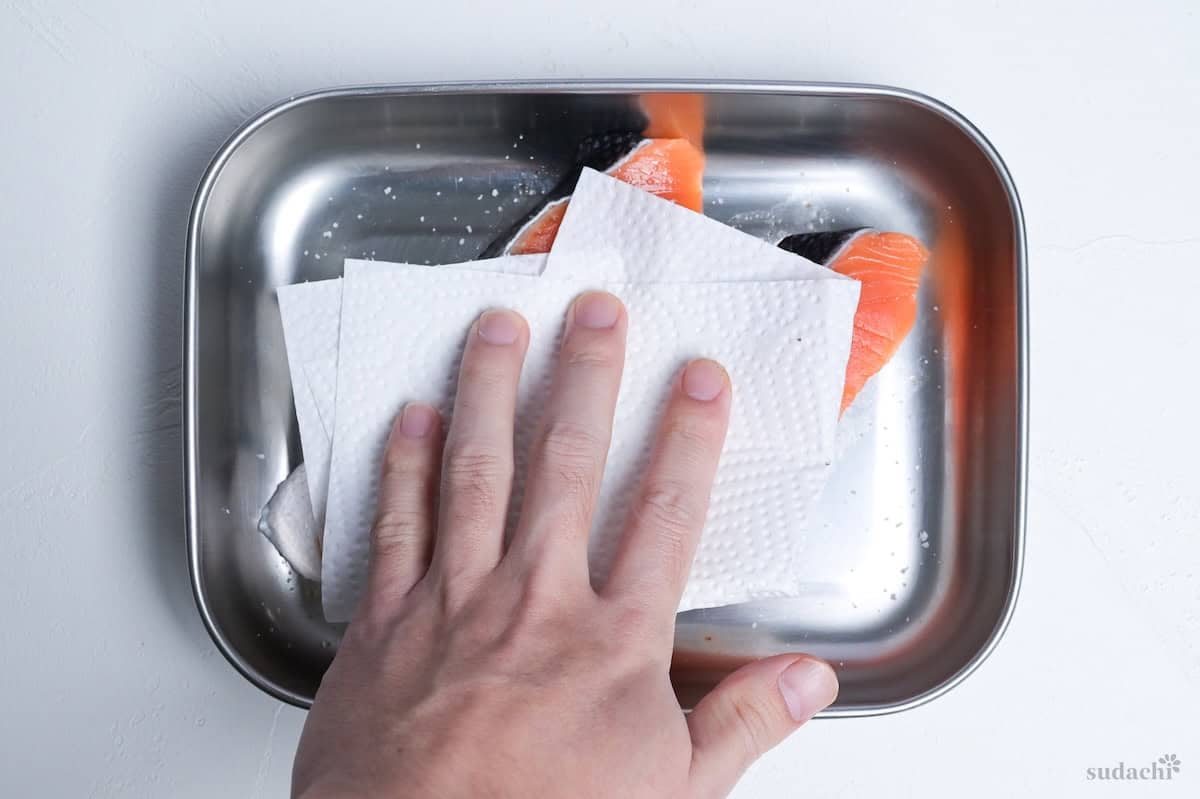 patting salted salmon fillets dry with kitchen paper