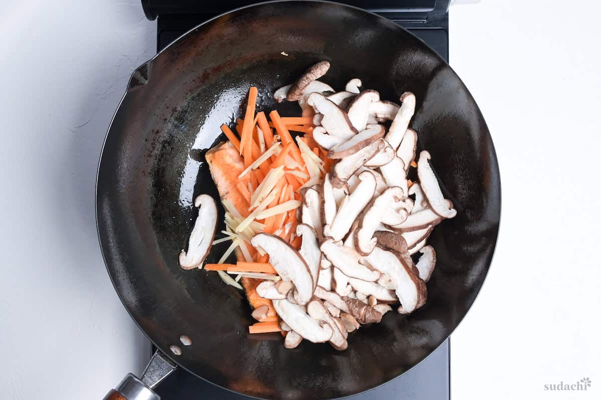 salmon, carrots, ginger and shiitake mushrooms frying in a wok