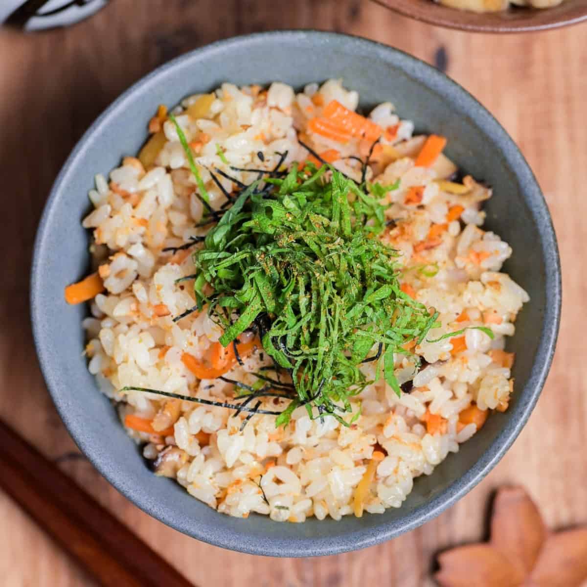 Salmon Maze Gohan topped with shredded nori and shiso leaves in a gray ceramic Japanese rice bowl