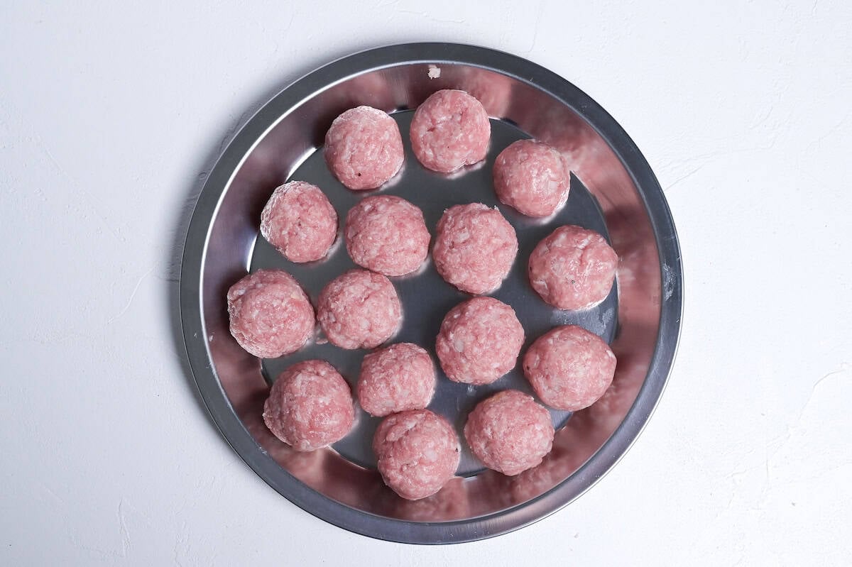 pork meatballs shape and arranged on a steel prep plate