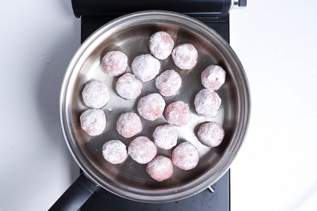 pork meatballs frying in a pan