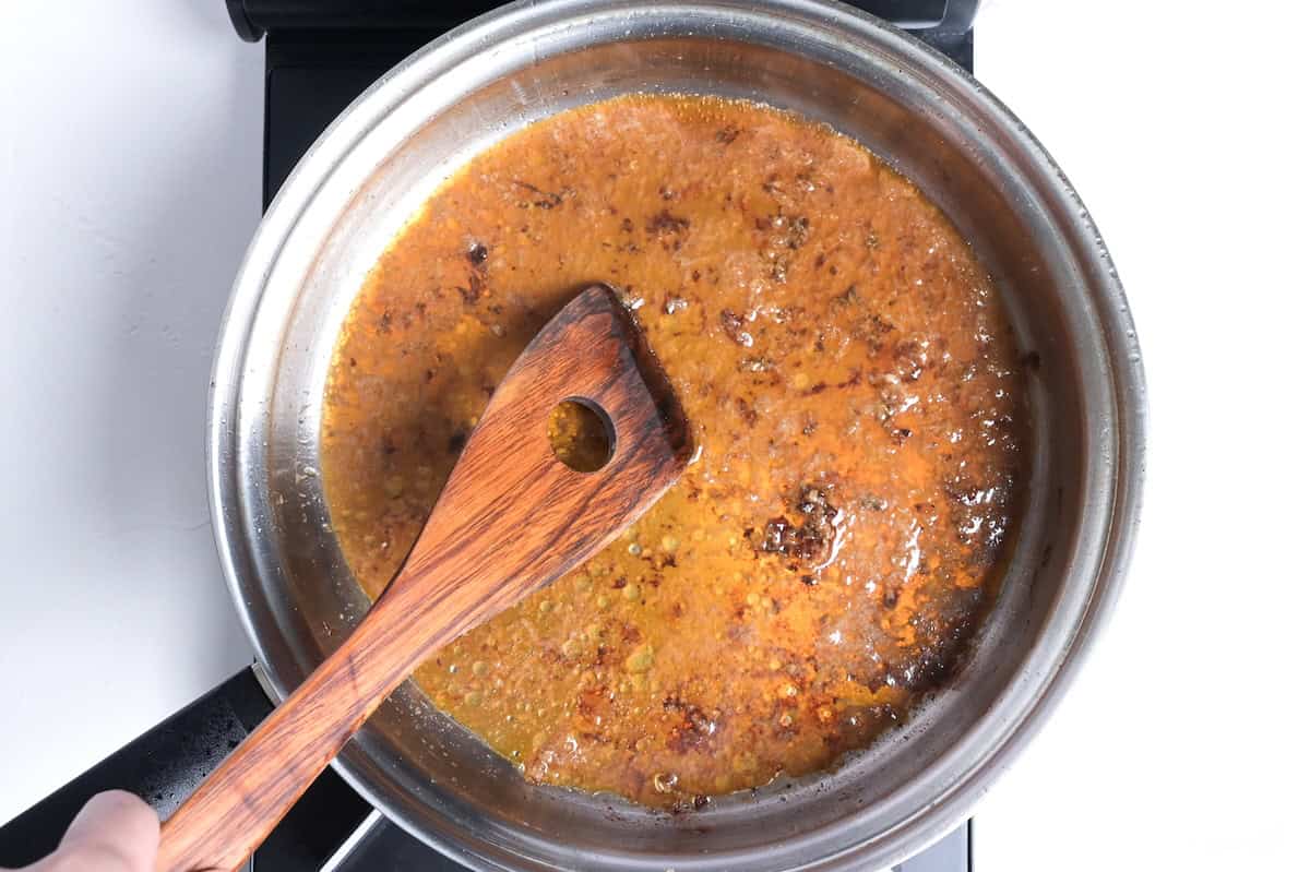 scraping fond in the pan after frying pork meatballs