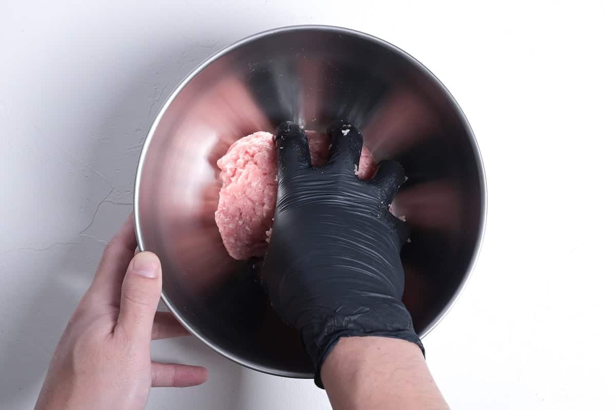 Kneading ground pork in a bowl to make teriyaki meatballs