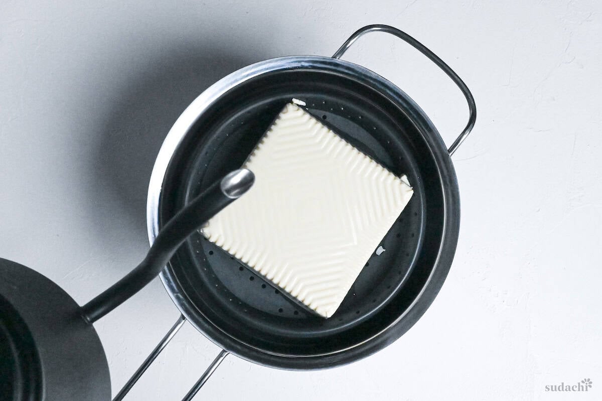 pouring boiling water over a block of silken tofu
