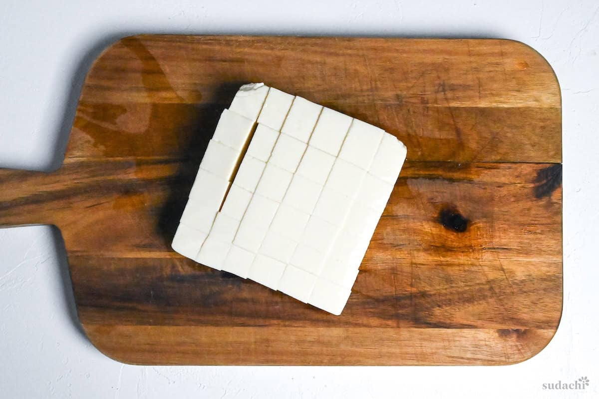 silken tofu block cut into cubes on a wooden cutting board