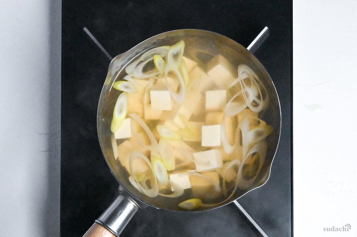 Japanese leek and tofu simmering in dashi in a pot on the stove top