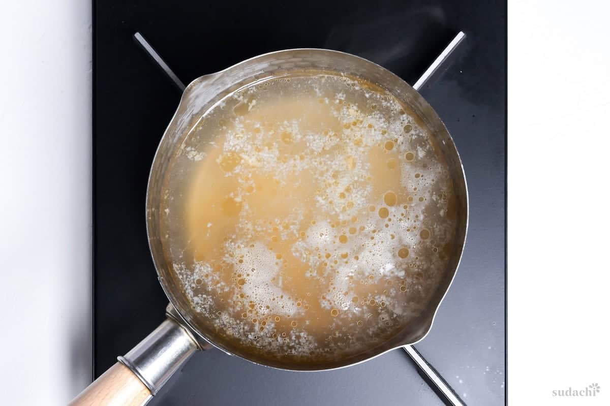 simmering wakame soup broth with condiments in a pan on the stove top