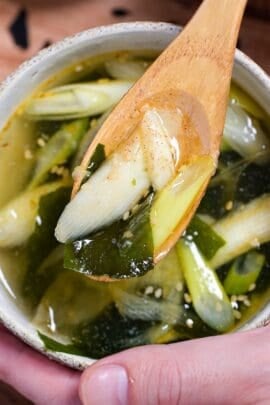 Close up of wakame soup on a light wooden spoon