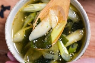 Close up of wakame soup on a light wooden spoon