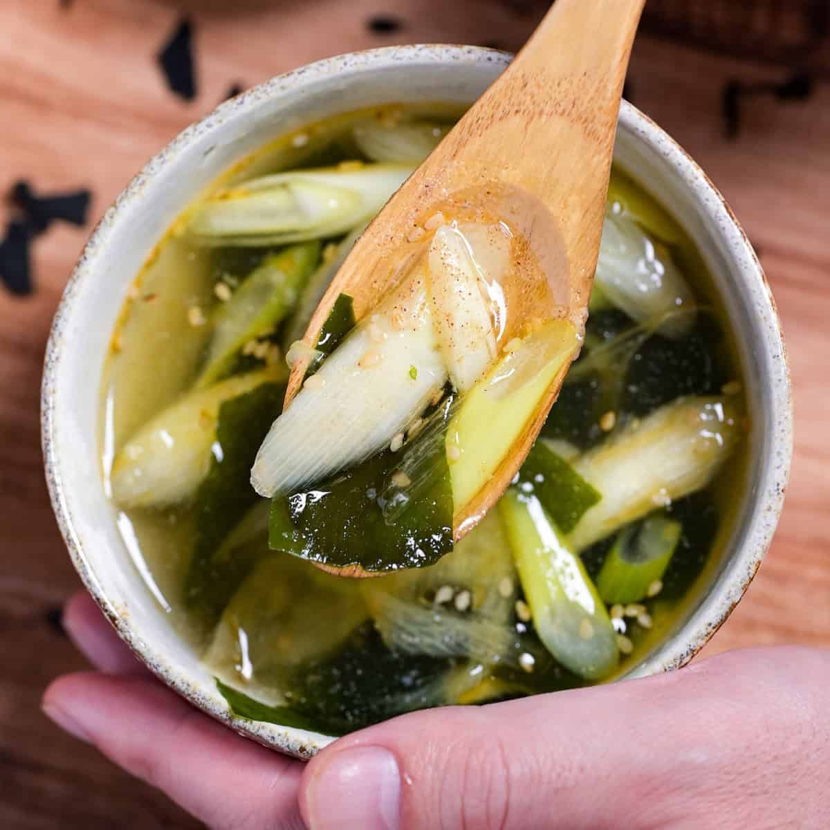 Close up of wakame soup on a light wooden spoon