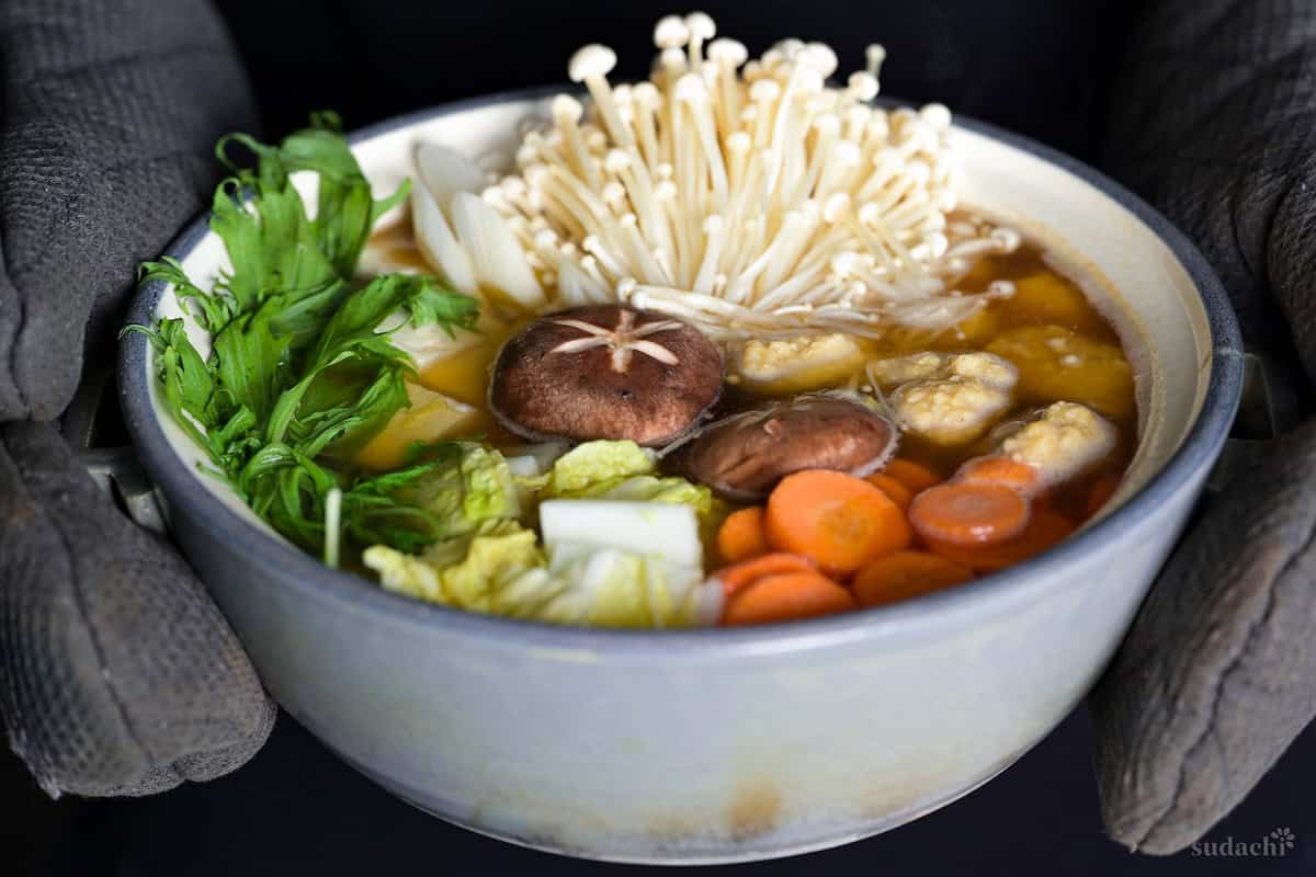 Yuto Omura holding chanko nabe in a gray/blue ceramic hot pot