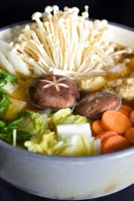 Yuto Omura holding chanko nabe in a gray/blue ceramic hot pot
