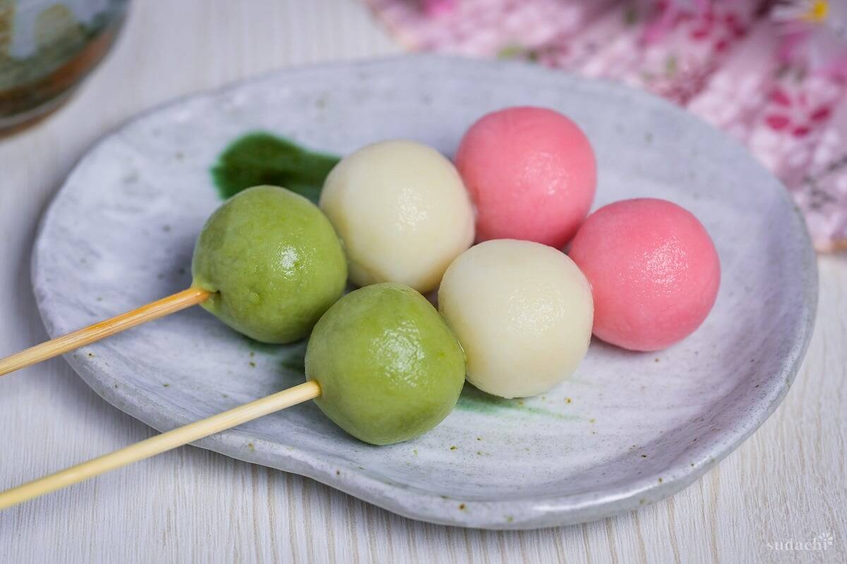 Two homemade tofu hanami dango on a gray plate with green brush design