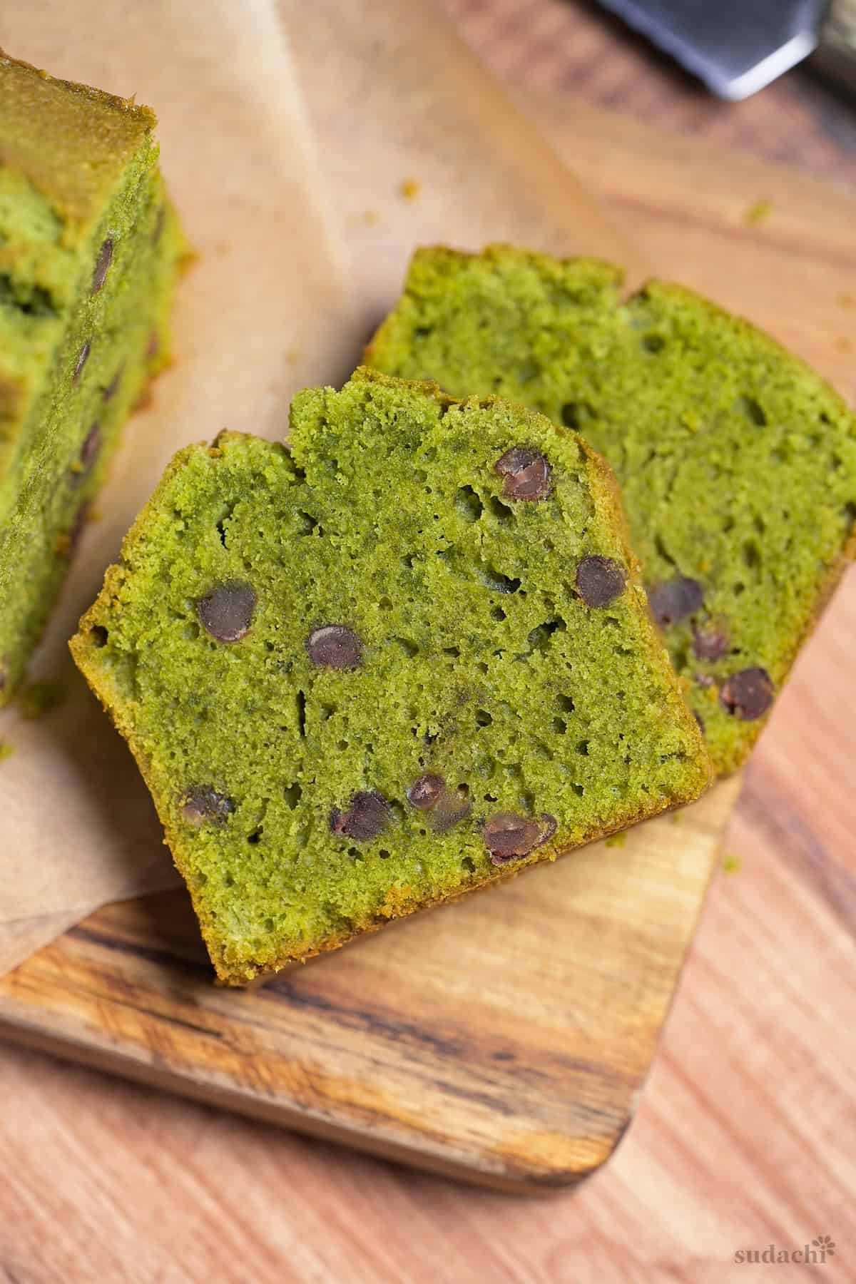 Two slices of matcha and adzuki bean pound cake stacked on a wooden cutting board
