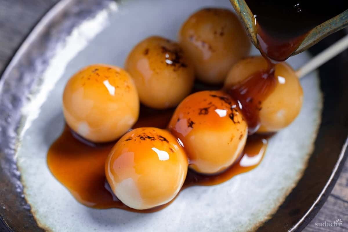 Pouring mitarashi sauce over homemade tofu dango